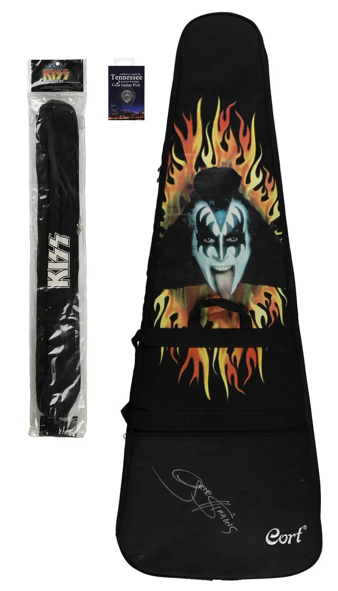 A guitar gig bag featuring an illustration of Gene Simmons with flame designs. The bag also has "Cort" and a signature printed on it. To the left, there is a packaged KISS guitar strap with a KISS logo and a pack of "Tortex" guitar picks above it.