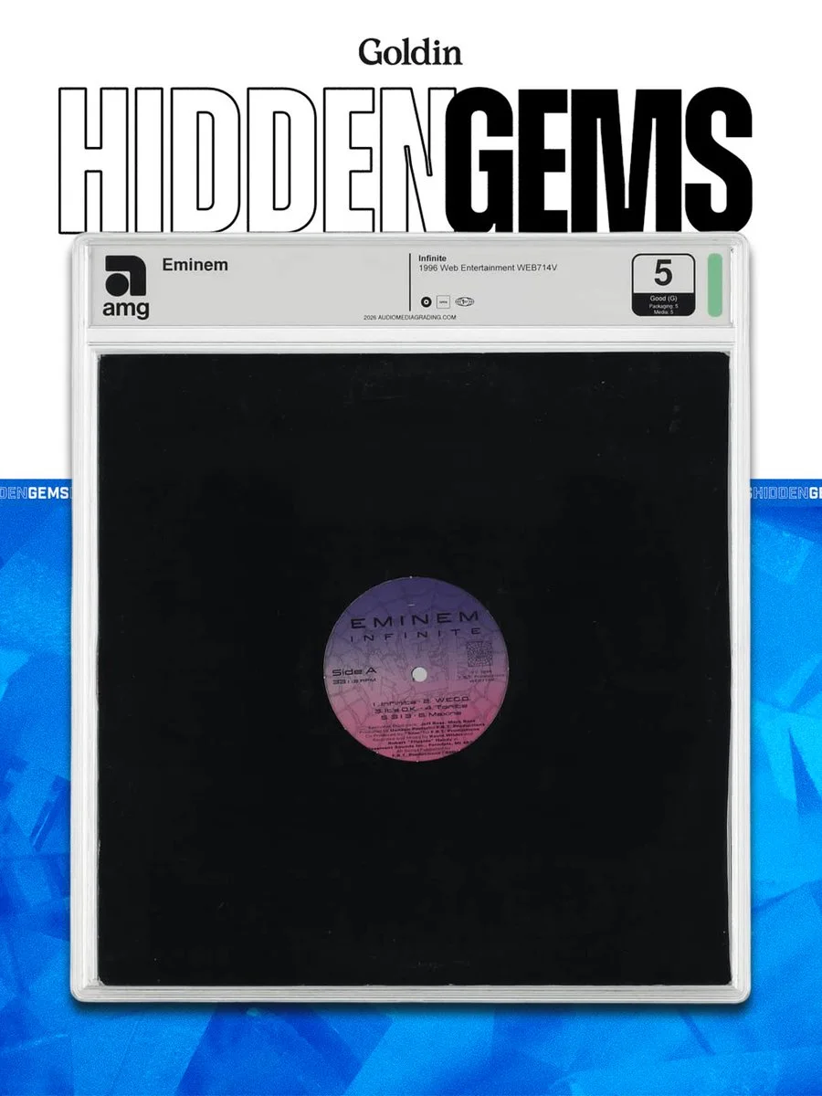 Vinyl record with Eminem label encased in a protective slab with rating. "Hidden Gems" and "Goldin" are displayed at the top. Blue geometric background.