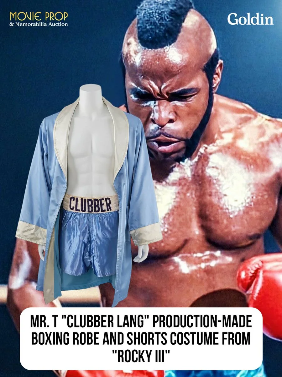 A boxing robe and shorts outfit labeled "Clubber Lang" is displayed in front of a figure in a boxing stance with gloves on. The robe is light blue with a white lining. Text on the image mentions "Mr. T 'Clubber Lang' Production-Made Boxing Robe and Shorts Costume from 'Rocky III'.