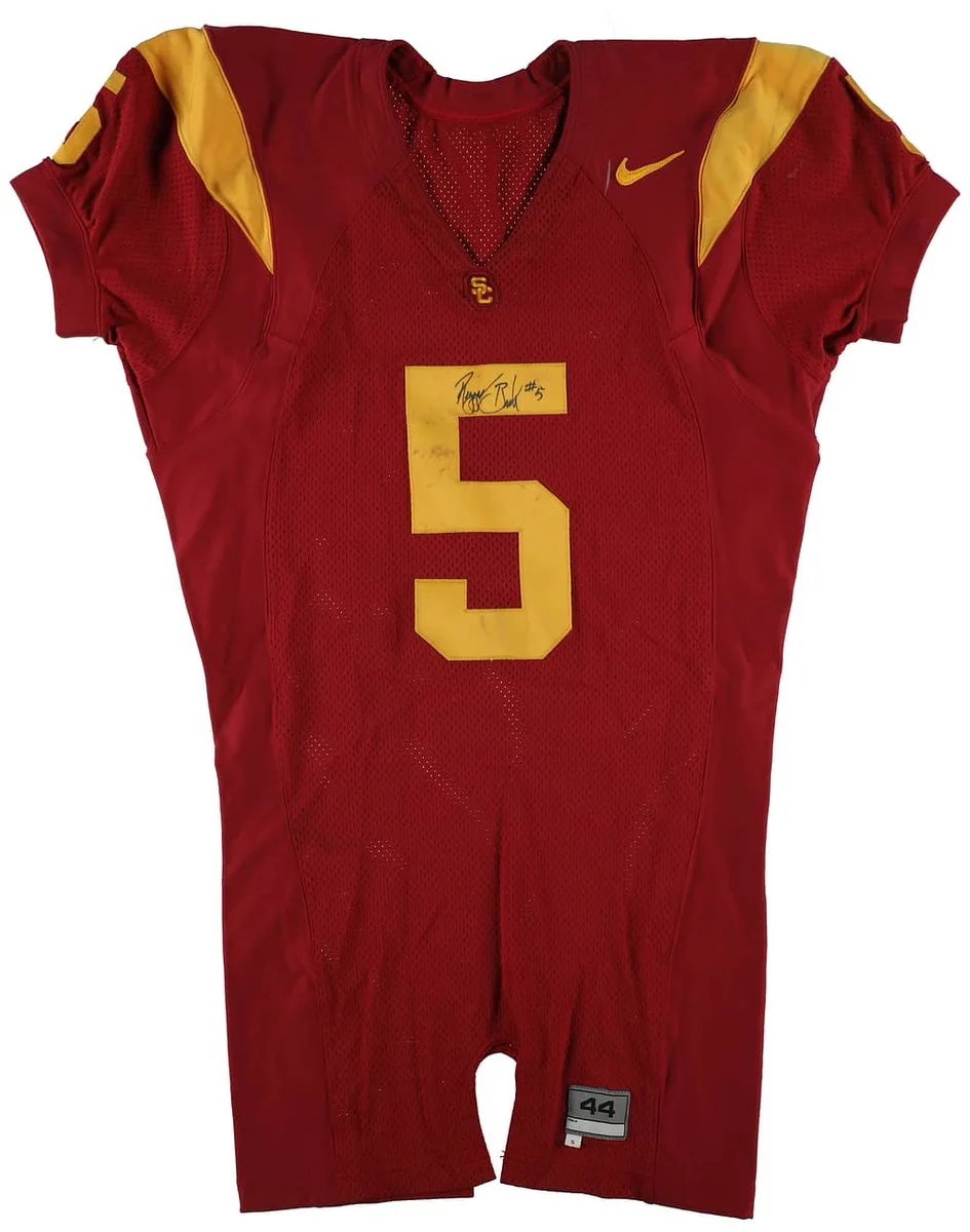 A red and gold football jersey with the number 5 on the front. It features the USC logo, a Nike symbol, and a signature near the number.